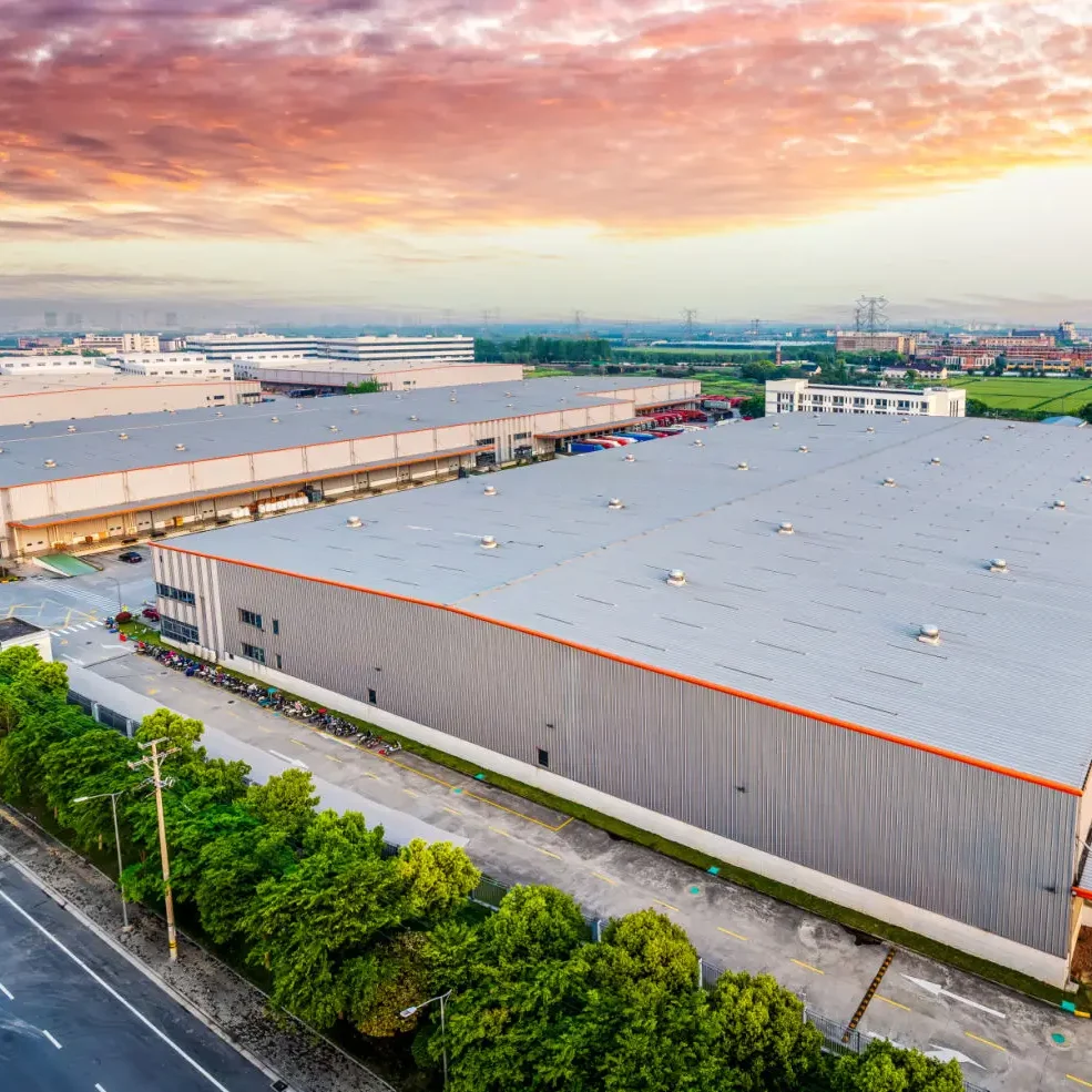 A large industrial warehouse under a colorful sunset sky.